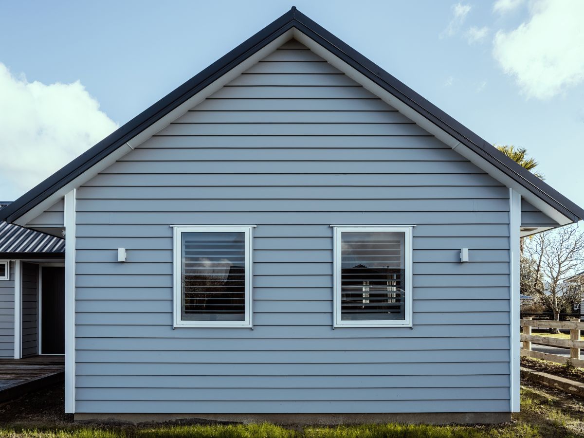 Gray suburban house with overlapping wood siding and gabled metal roof. Front view.