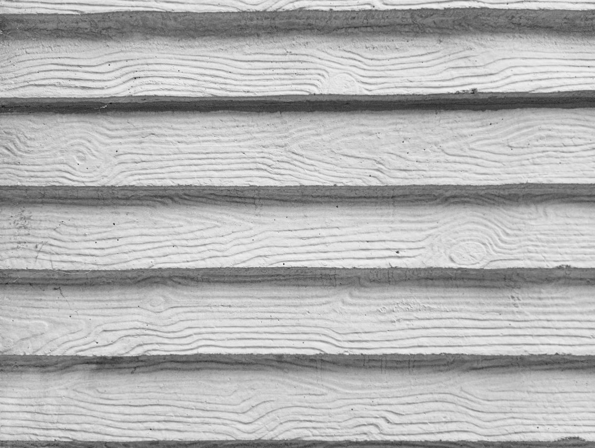Texture of horizontal siding panels with a realistic white wood grain pattern. Close-up photography of modern concrete or plastic building cladding